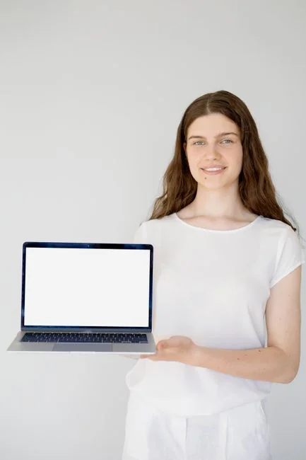 Woman in floral dress shopping online with a laptop and credit card indoors.